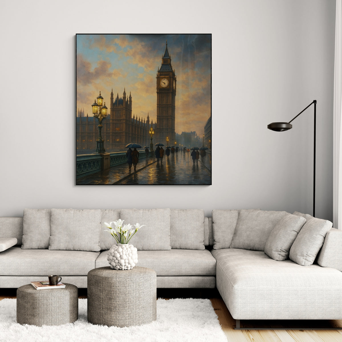 A framed oil painting of Big Ben and the Houses of Parliament in London, displayed on a wall above a modern gray sofa and a round gray table with a vase of flowers on it.