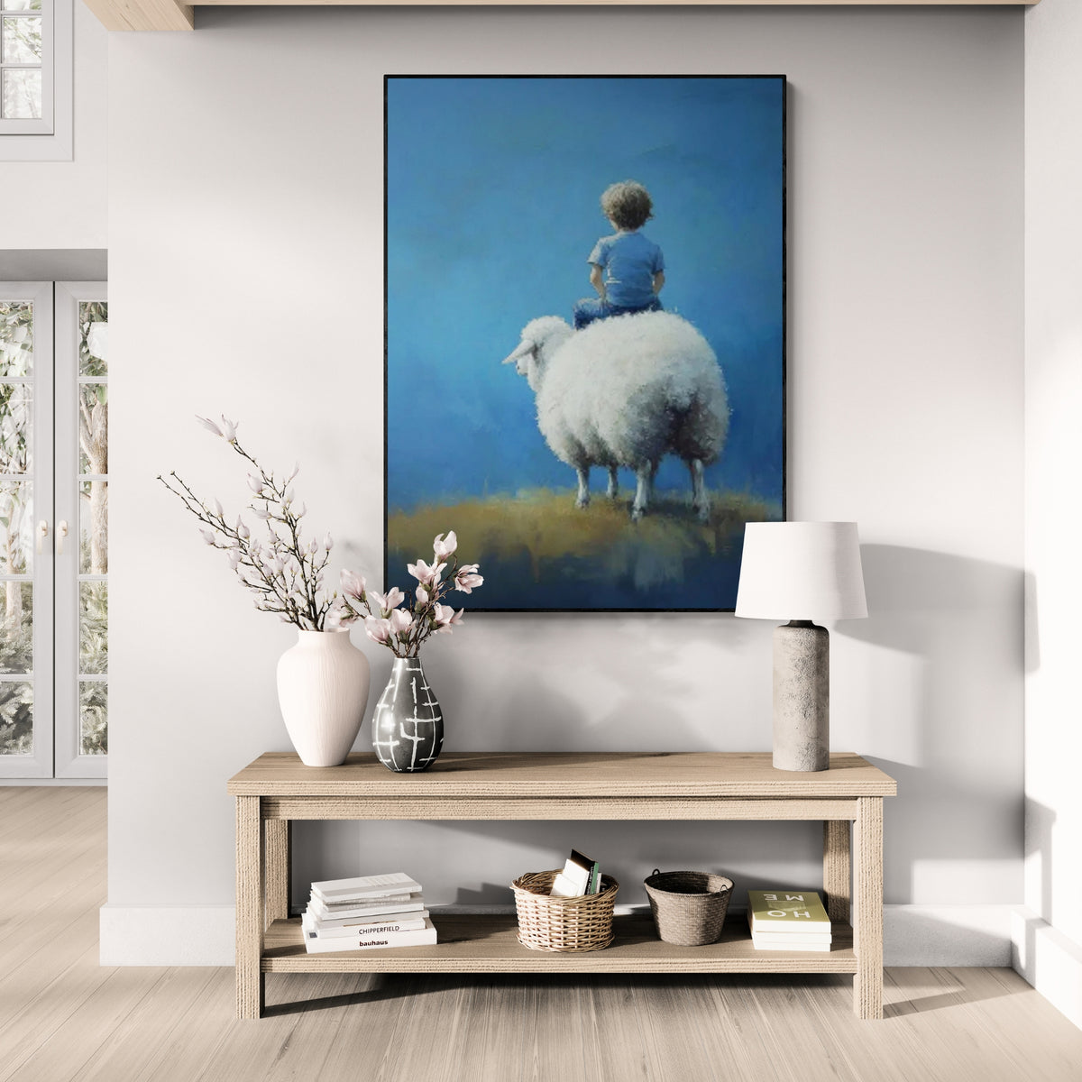 A painting depicting a young boy sitting on a fluffy sheep with a serene blue backdrop, placed above a wooden console table in a bright room.
